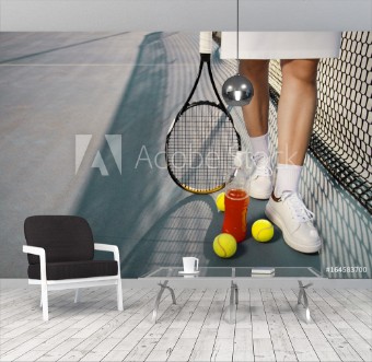 Picture of Tennis concept  woman legs next to tennis balls and refreshing drink next to net  copy space  outdoors 